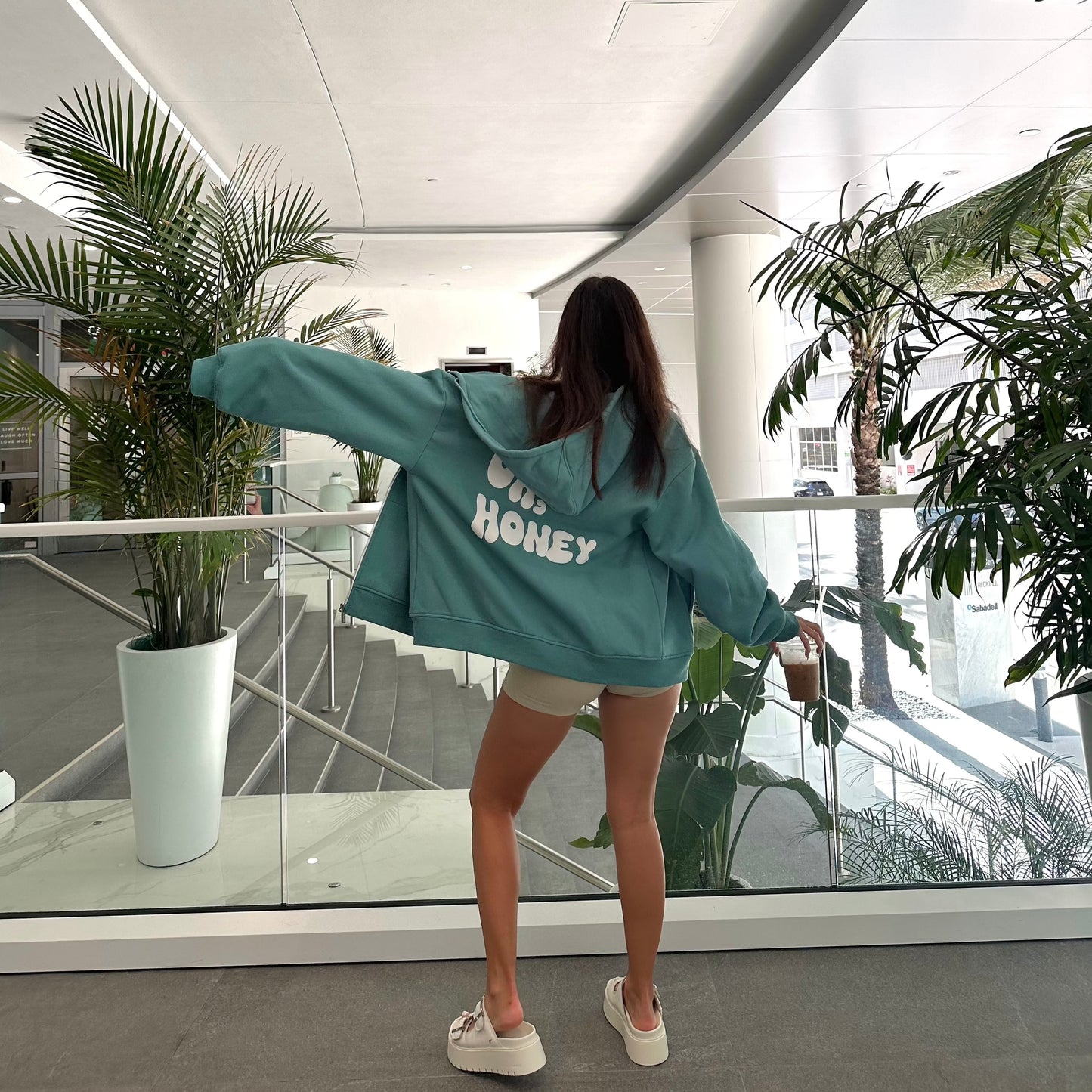 honeydew lounge girl wearing oversized girly sweatshirt that says Oh Honey